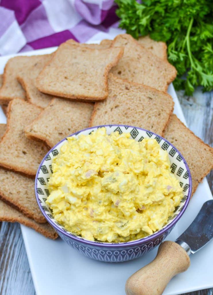 ham and egg salad in a purple bowl surrounded by pieces of party toast