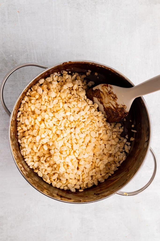 crisp rice cereal being added to a pot of melted chocolate sauce