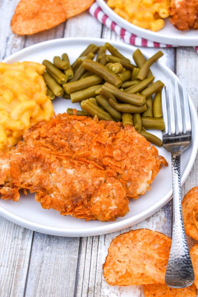 barbecue potato chip chicken tenders on a white plate with mac and cheese and green beans on the side