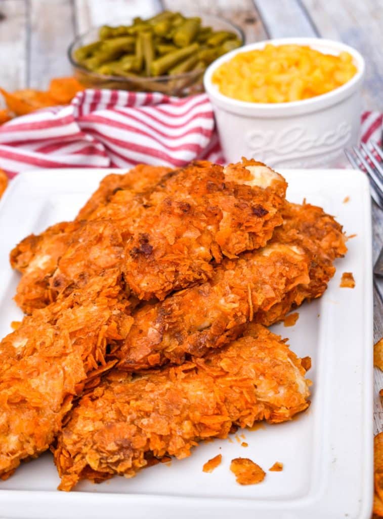 baked barbecue chip chicken tenders stacked on a white platter
