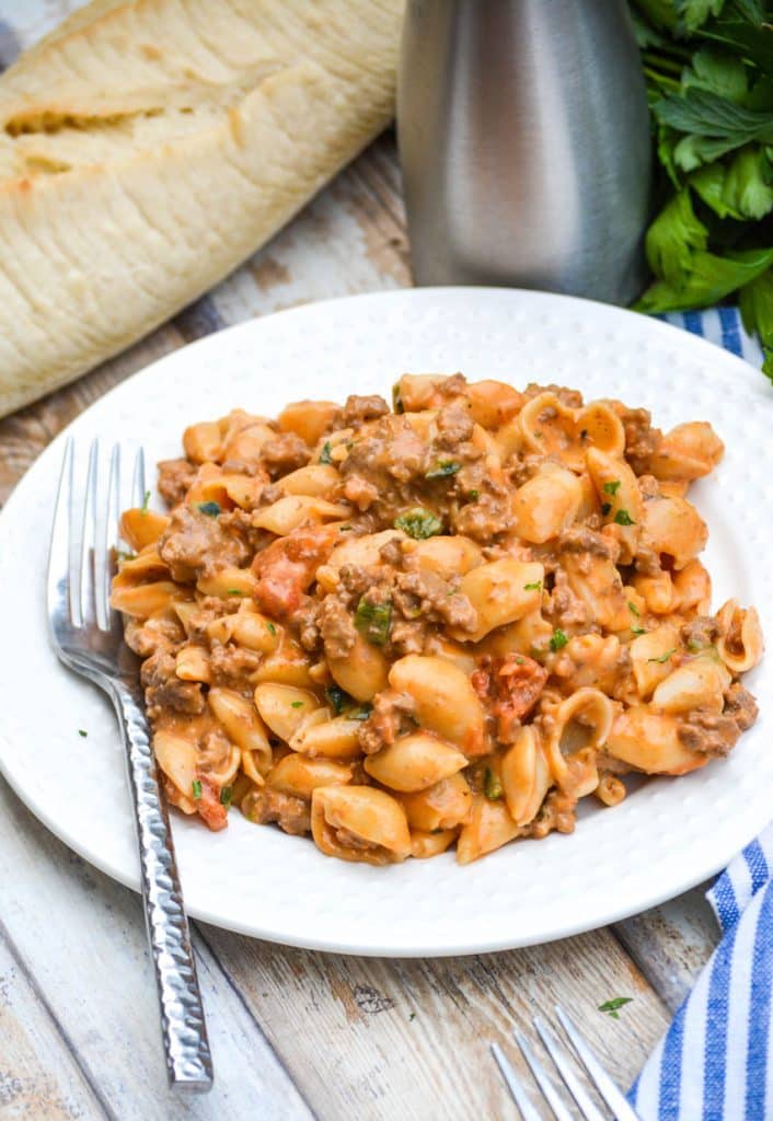 mac and cheese goulash on a white plate with a silver fork on the side