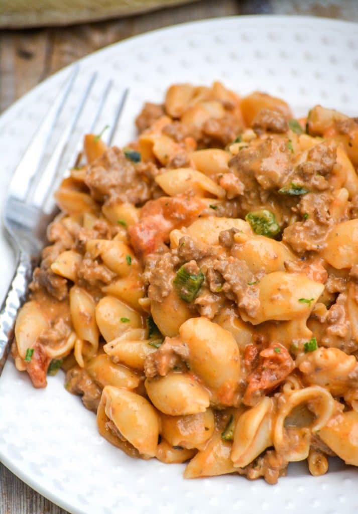 mac and cheese goulash on a white plate with a silver fork on the side