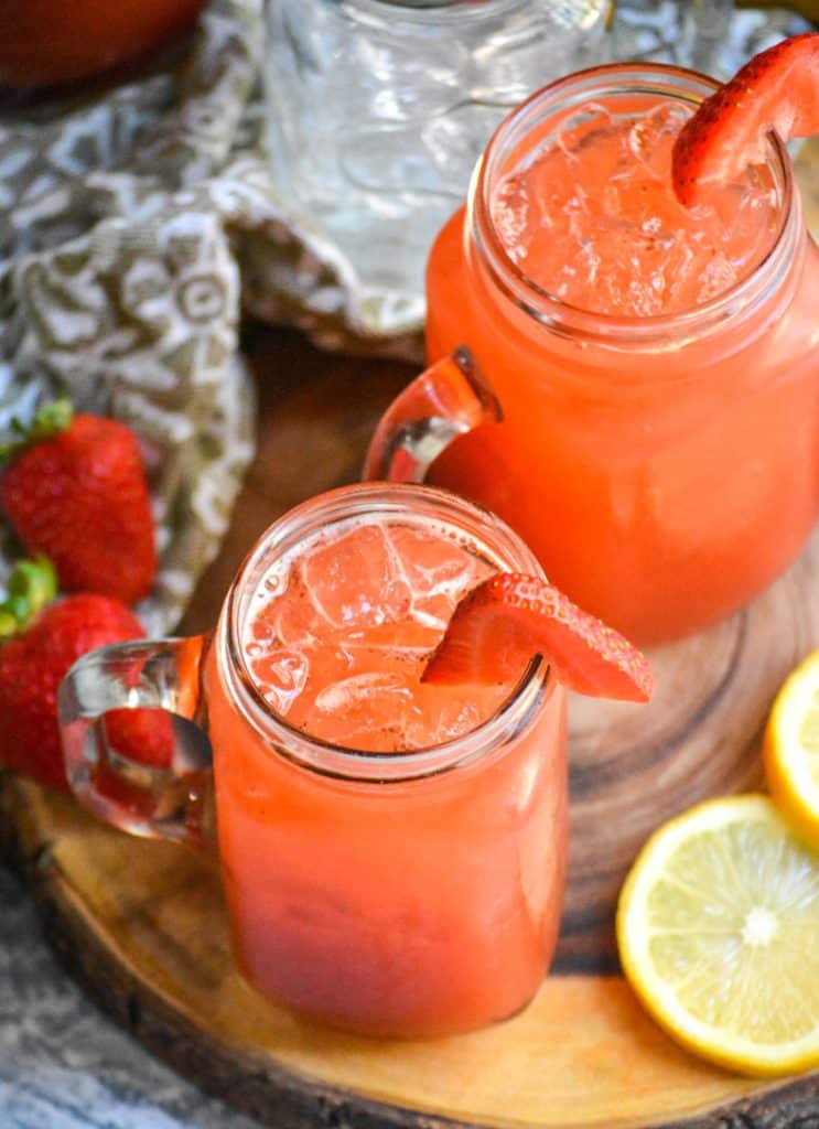 easy strawberry lemonade in glasses over ice on a wooden cutting board