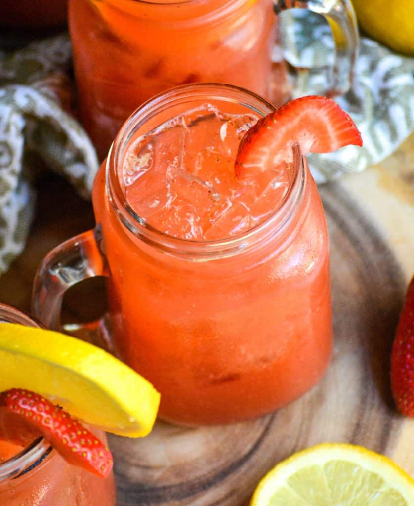ice filled glasses of strawberry lemonade garnished with fresh lemon & strawberry slices