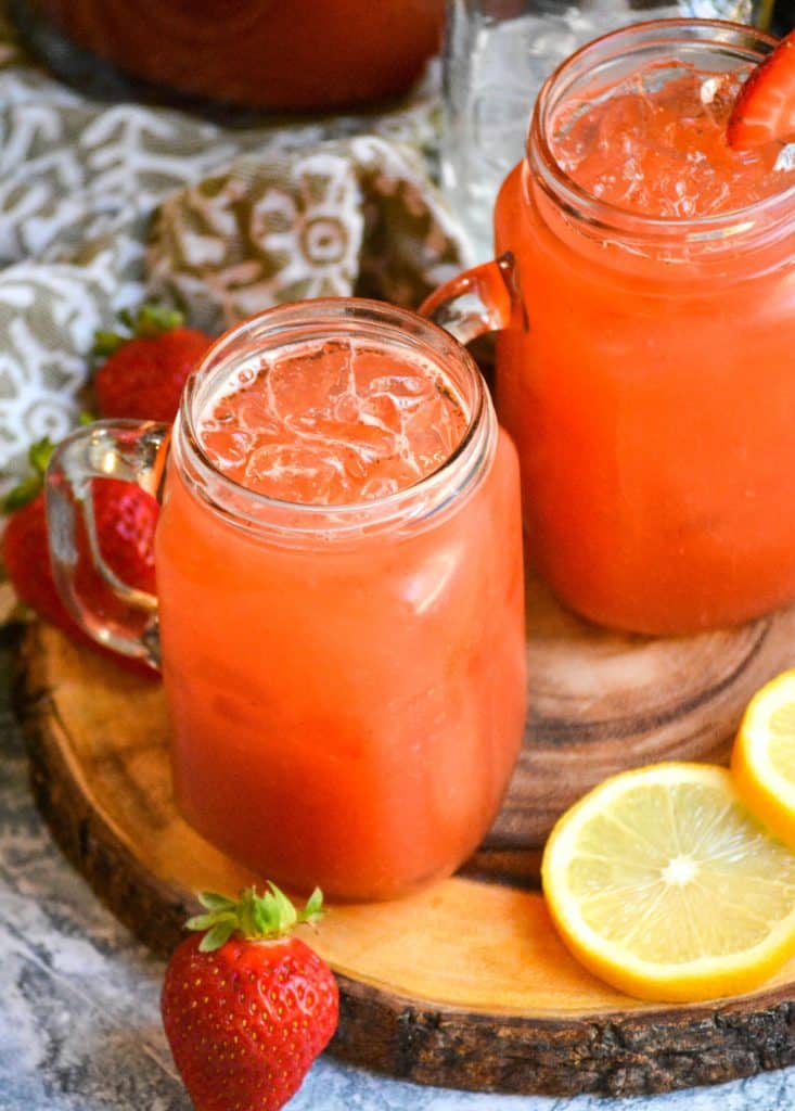 easy strawberry lemonade in glasses over ice on a wooden cutting board