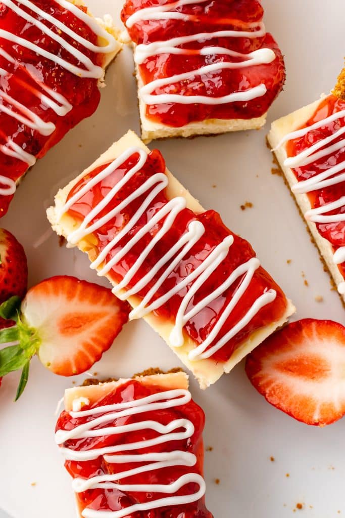 cut Philadelphia strawberry cheesecake snack bars arranged next to fresh berries