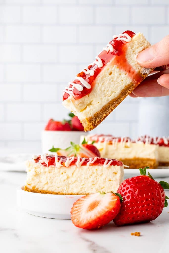 a hand holding up a copycat philadelphia cheesecake snack bar
