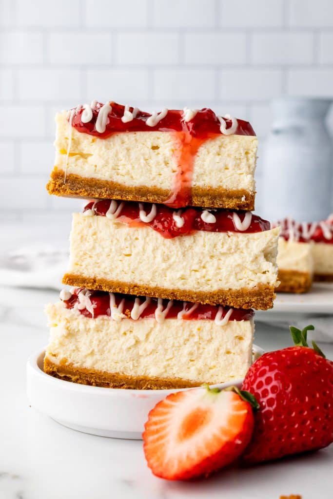 Philadelphia strawberry cheesecake snack bars stacked on top of each other on a small white snack plate
