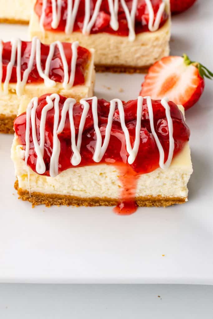 cut Philadelphia strawberry cheesecake snack bars arranged next to fresh berries