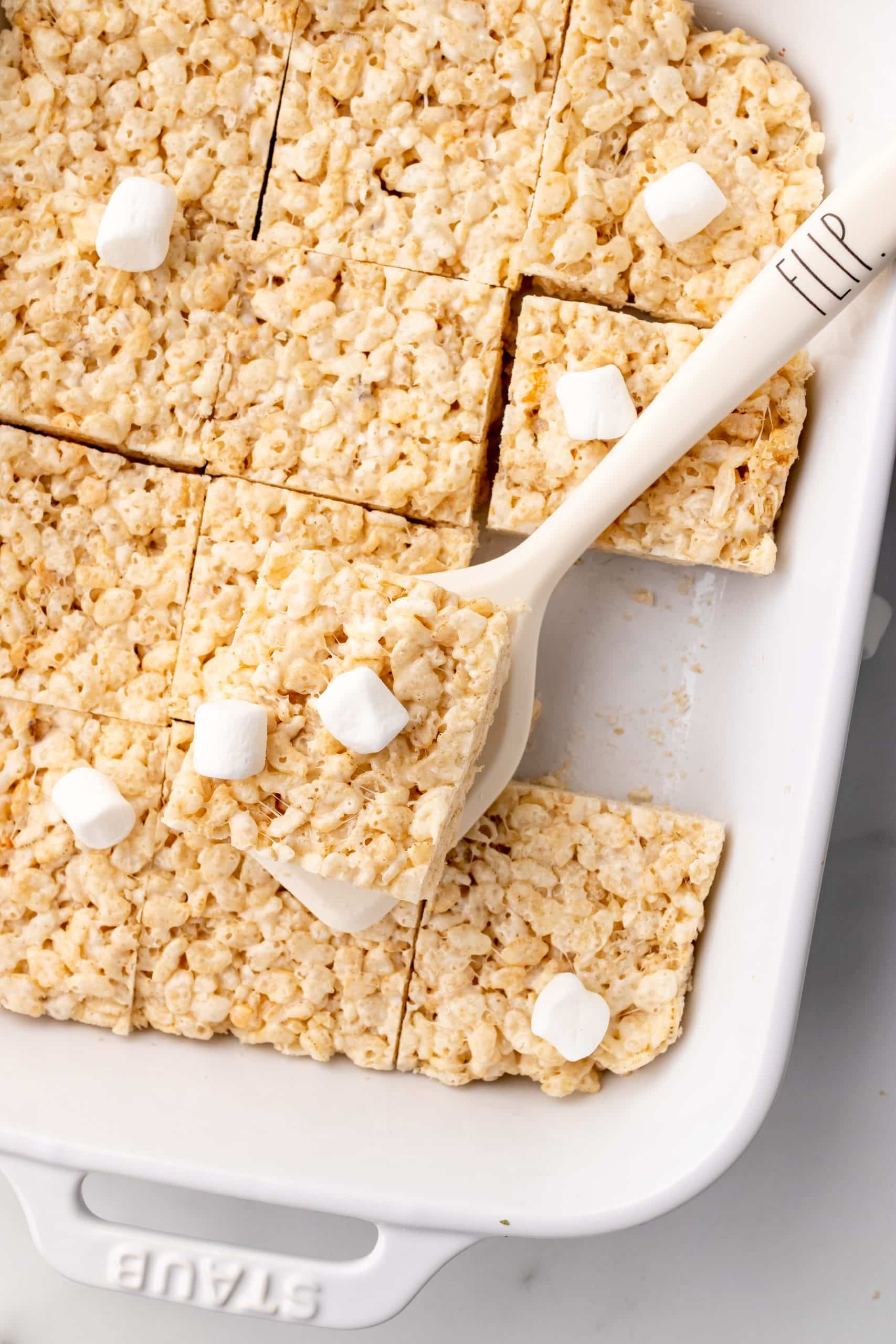 a white spatula holding up a marshmallow topped rice krispies treat square