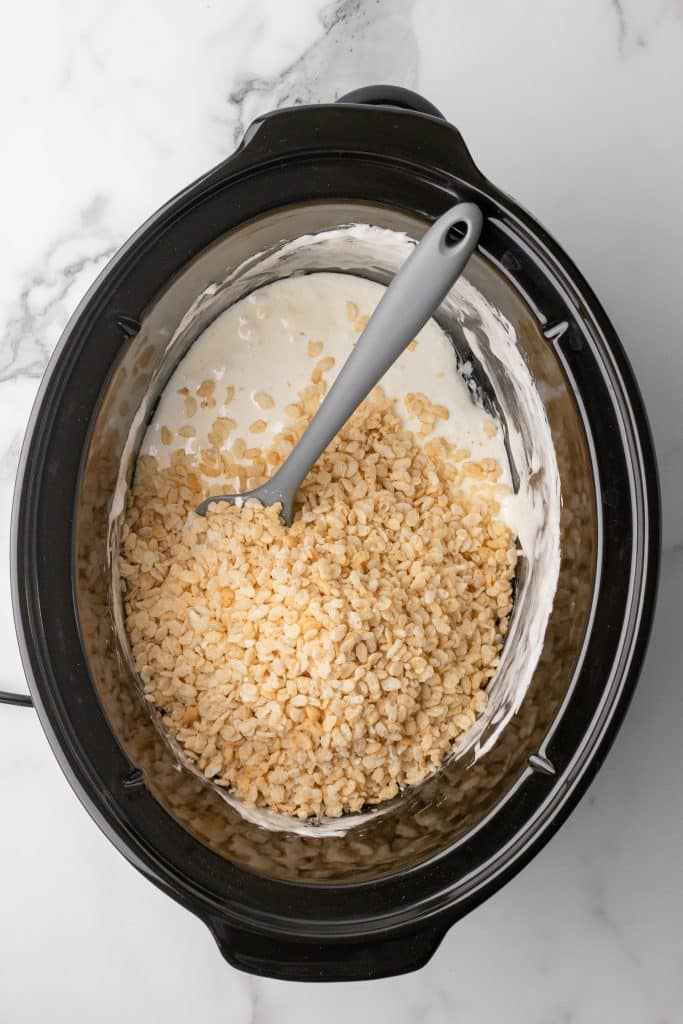 rice krispies and melted marshmallows in the black bowl of a slow cooker