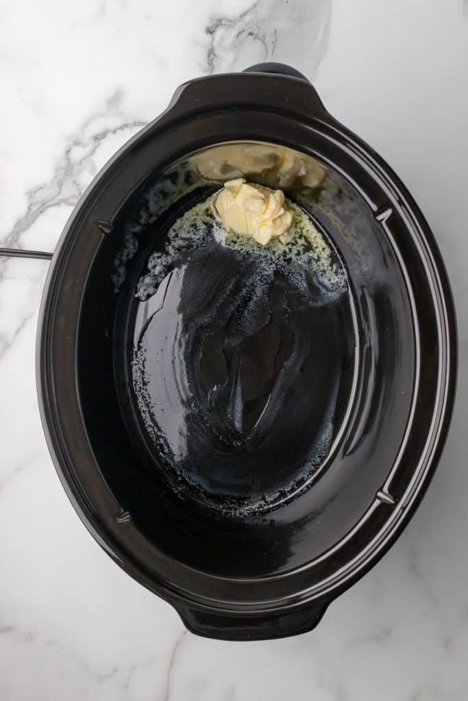 butter melting in the black bowl of a crockpot
