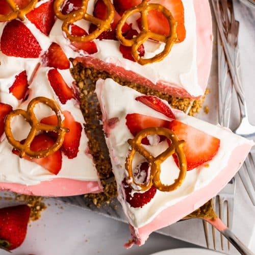 a piece of strawberry pretzel pie being removed from the whole on a silver serving spatula