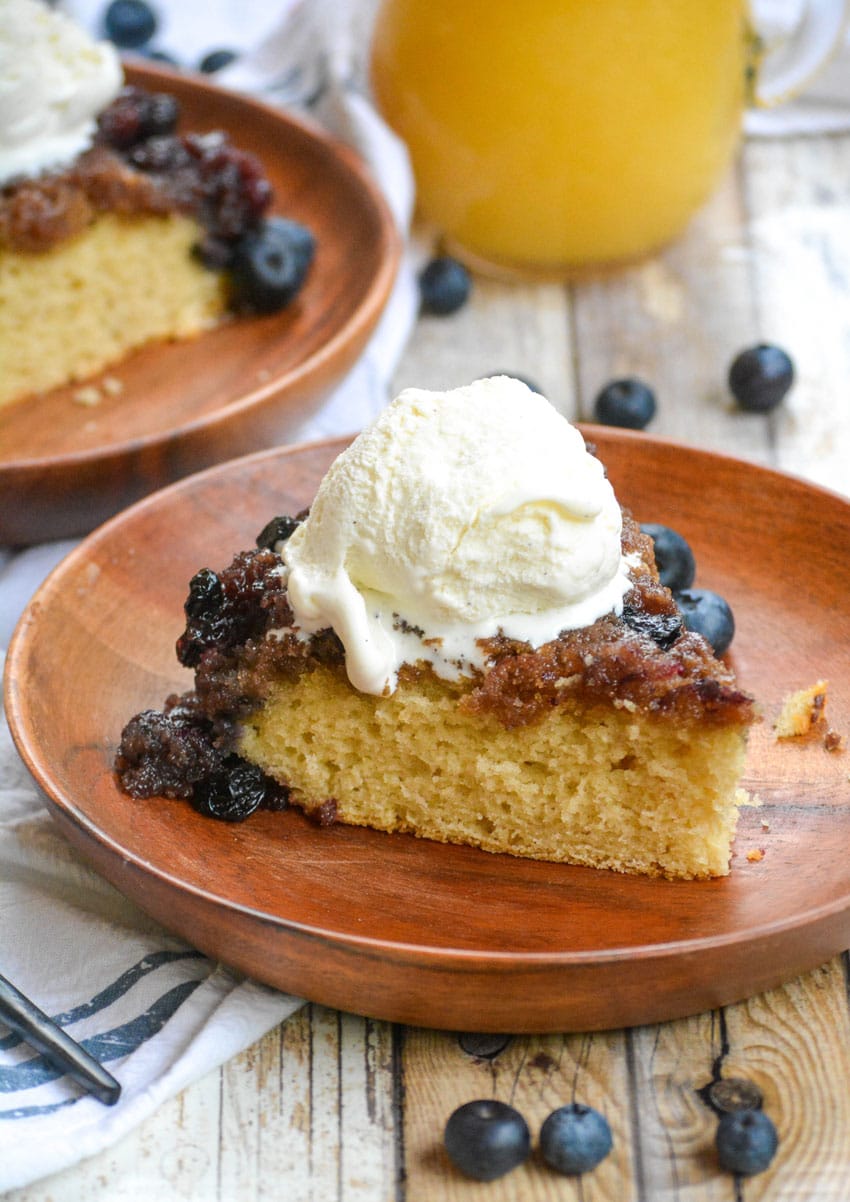 blueberry upside down cake on a wooden plate topped with ice cream