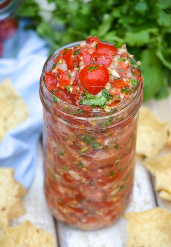 a glass jar filled with fresh tomato salsa