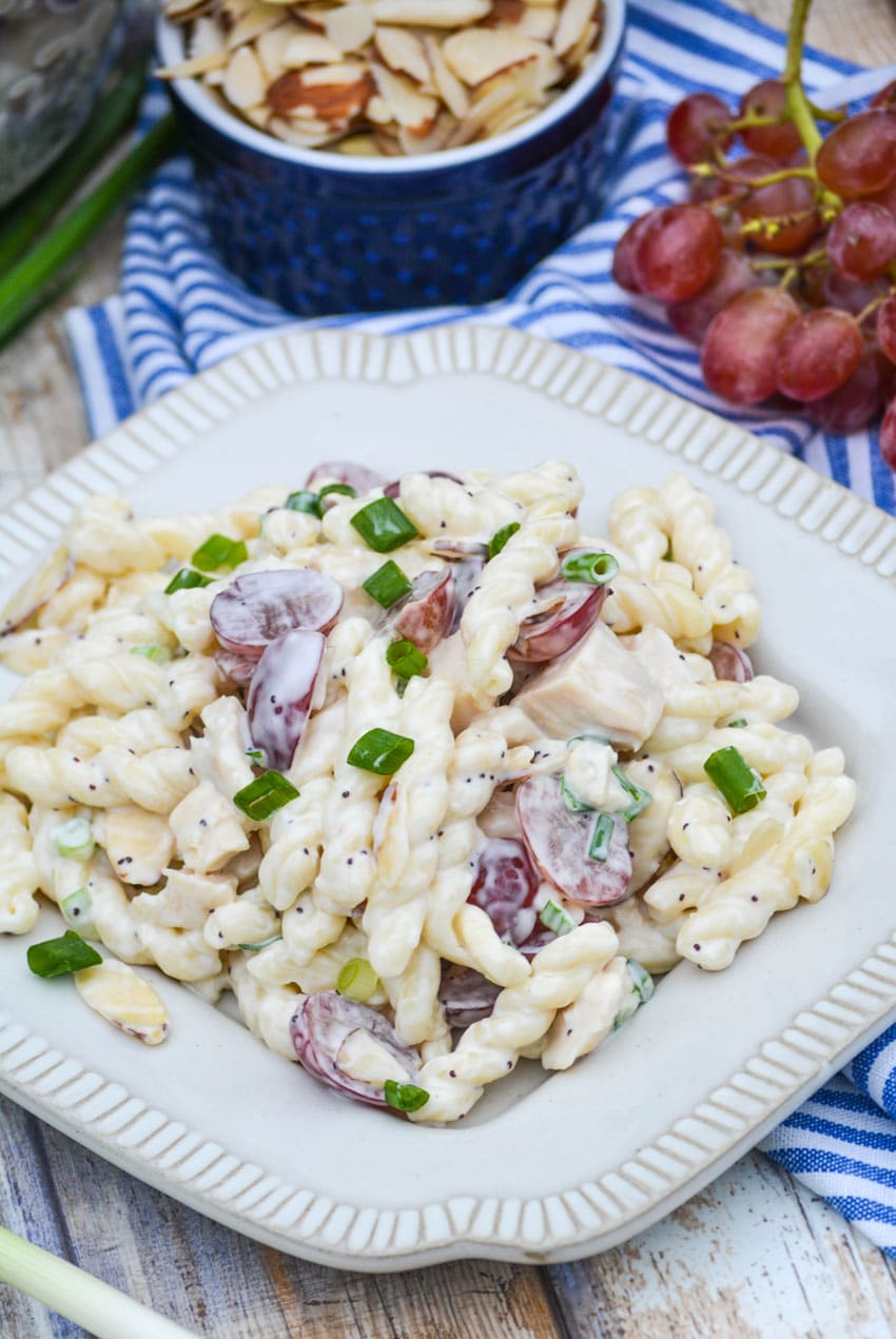 creamy poppy seed chicken pasta salad with grapes on a white plate