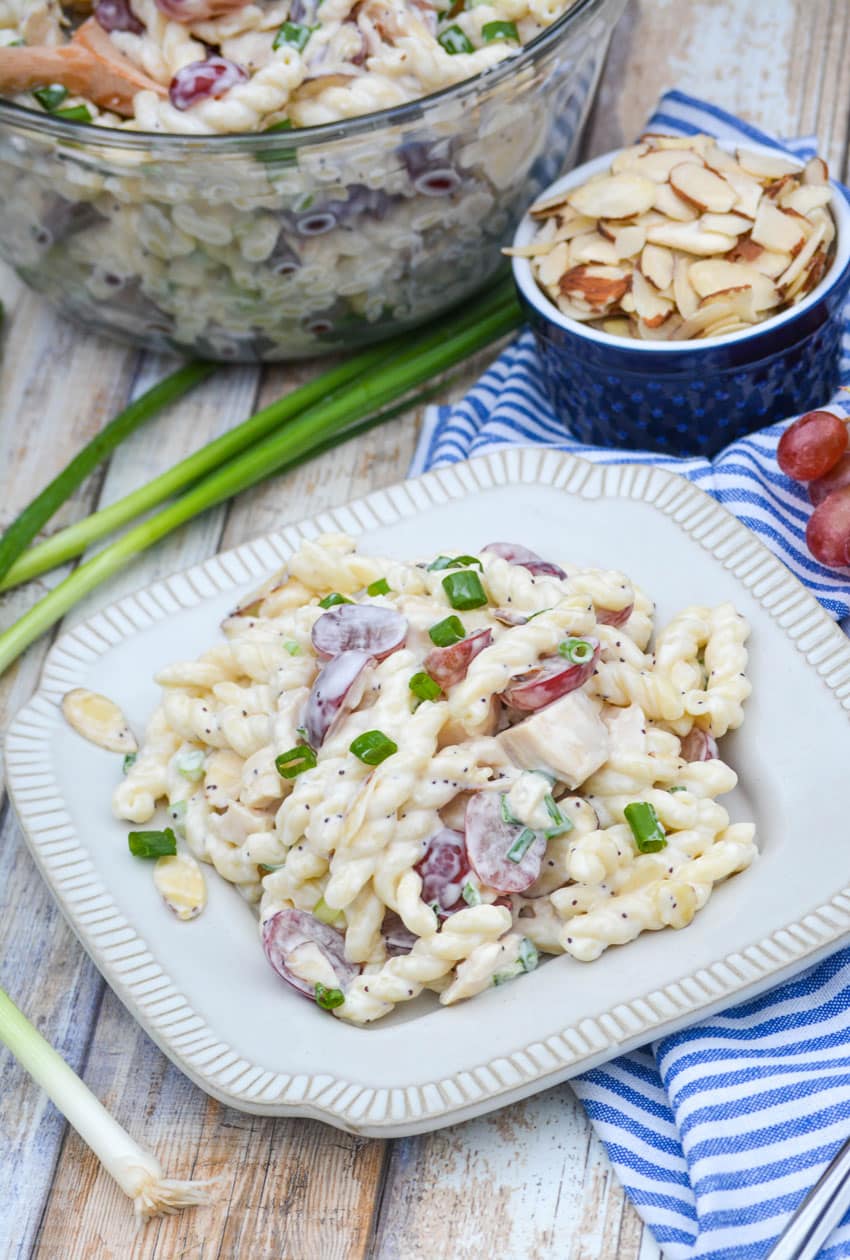 creamy poppy seed chicken pasta salad with grapes on a white plate