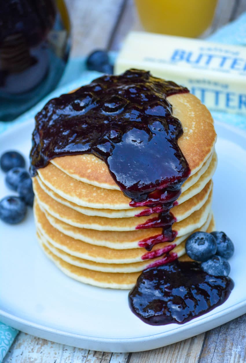 easy blueberry syrup poured over a stack of pancakes
