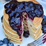 easy blueberry syrup poured over a stack of pancakes