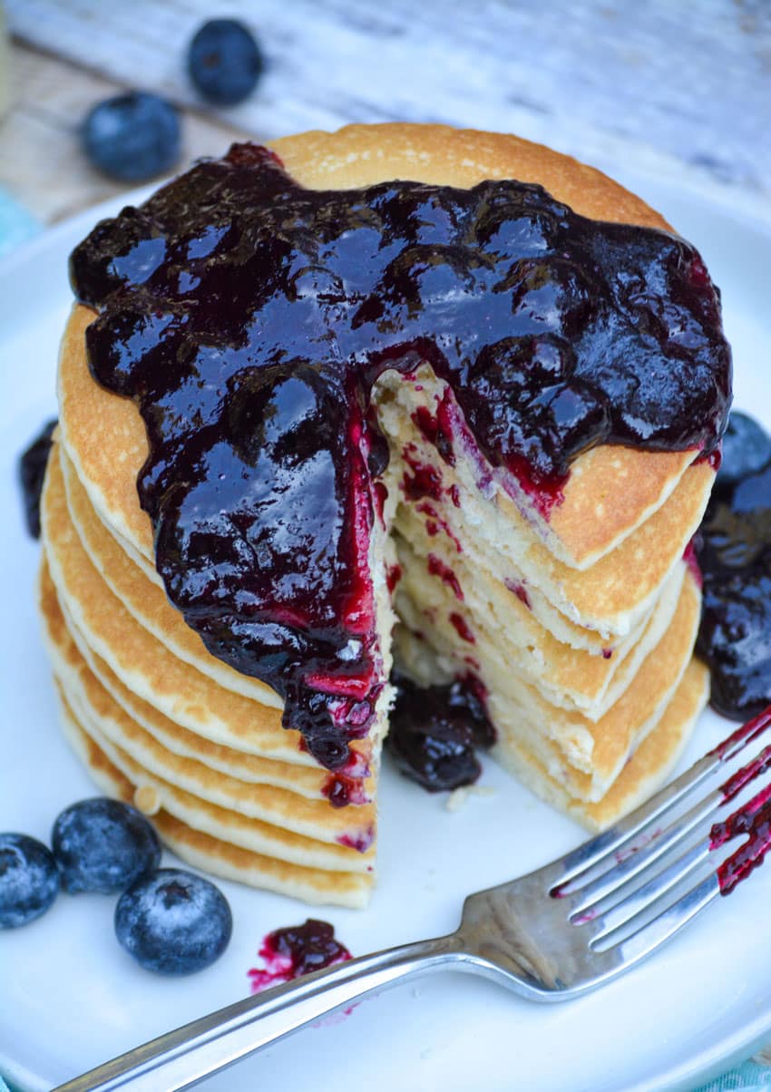 easy blueberry syrup poured over a stack of pancakes