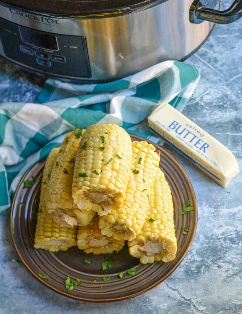slow cooker corn on the cob pieces stacked on a brown plate
