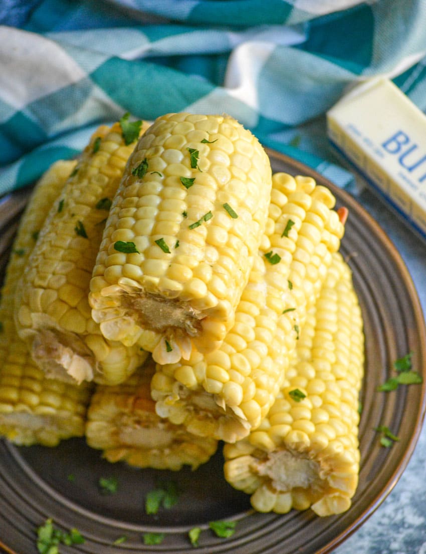 Slow Cooker Corn On The Cob slow cooker corn on the cob pieces stacked on a brown plate