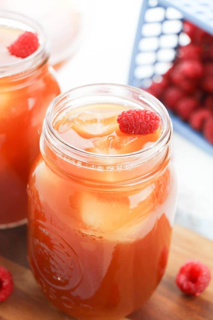 raspberry iced tea in glass mason jars with a fresh raspberry for garnish