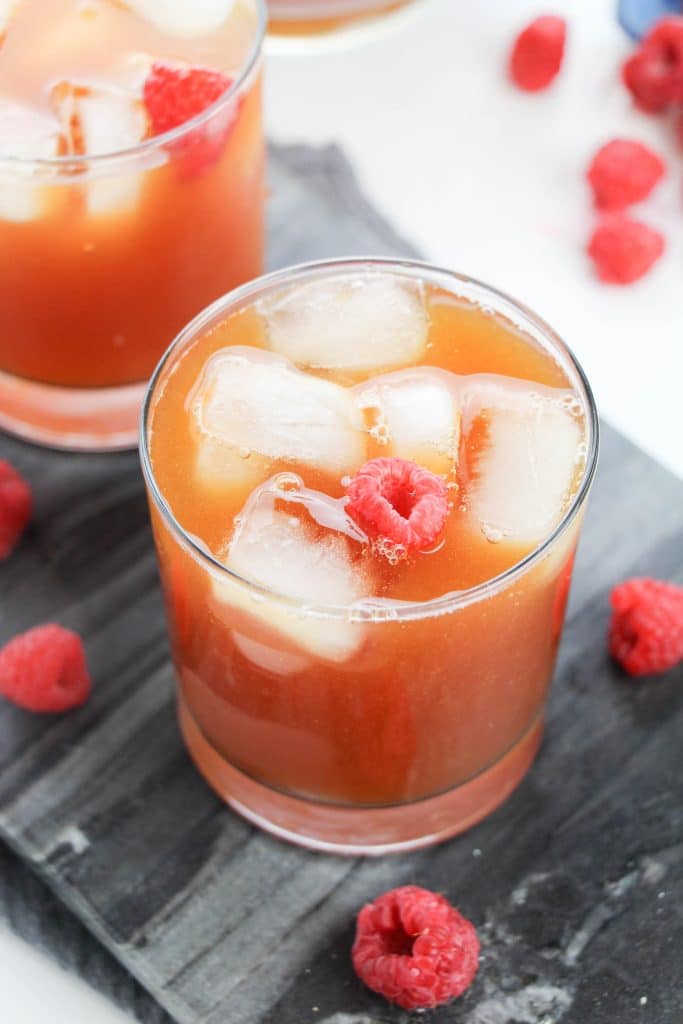 raspberry iced tea in glasses surrounded by fresh berries