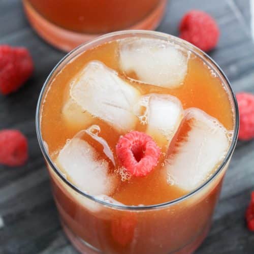 raspberry iced tea in glasses surrounded by fresh berries