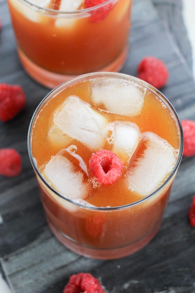 raspberry iced tea in glasses surrounded by fresh berries