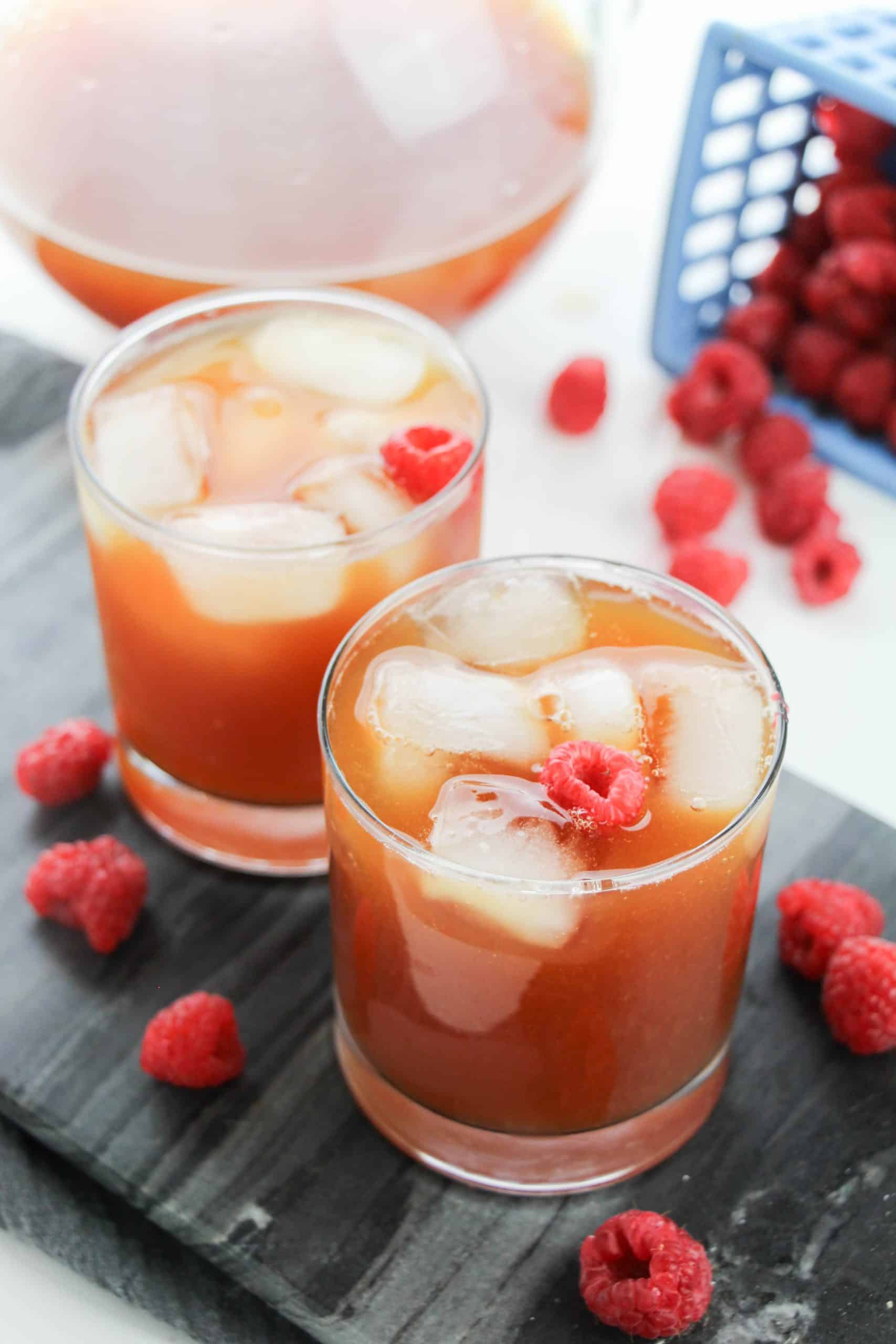 raspberry iced tea in glasses surrounded by fresh berries