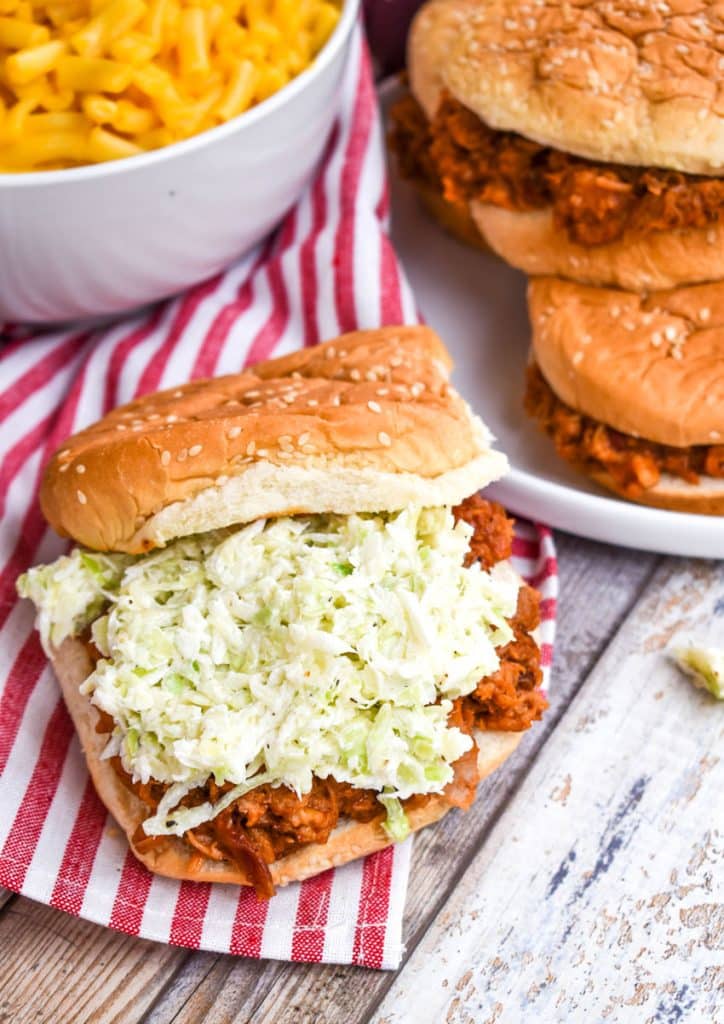 2 ingredient coleslaw spread over pork barbecue on a sesame seed bun