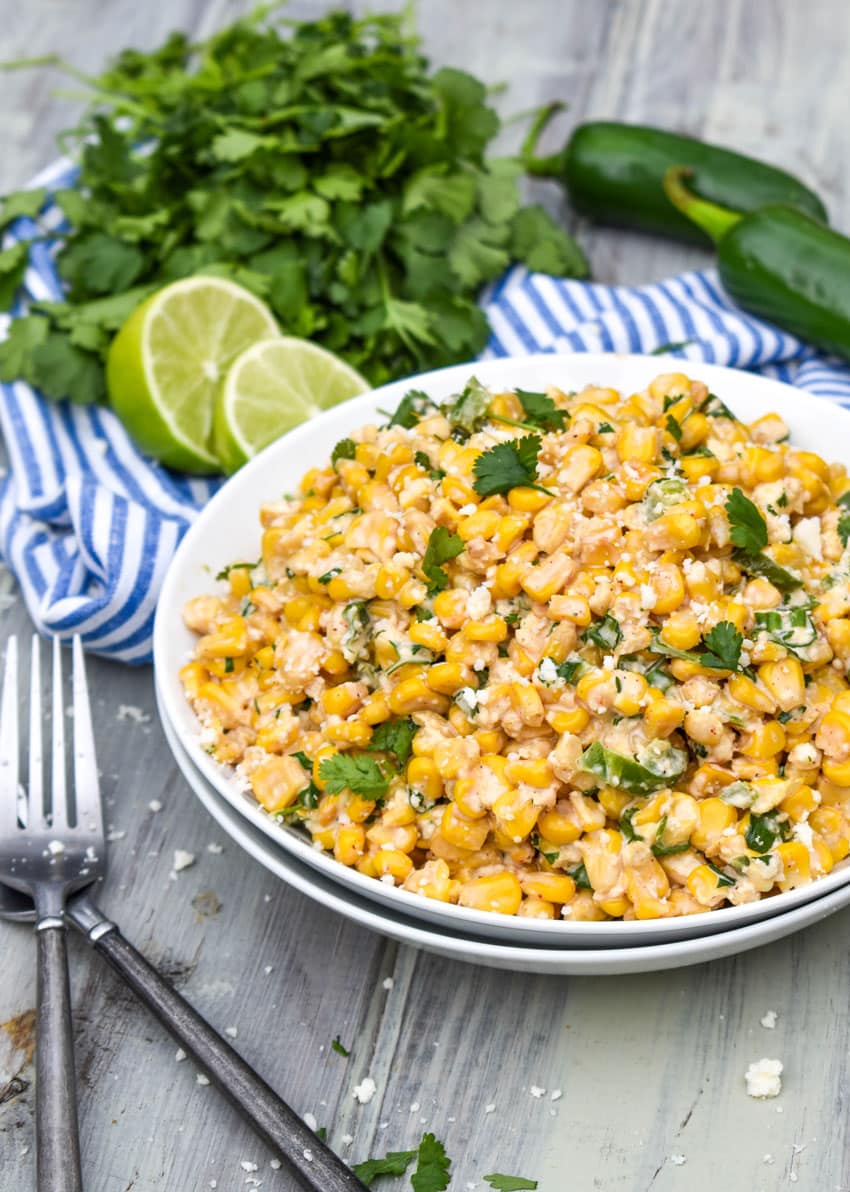 esquites served in a white bowl with two silver forks on the side
