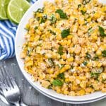 mexican street corn salad in a white bowl topped with crumbled cotija cheese and fresh cilantro leaves