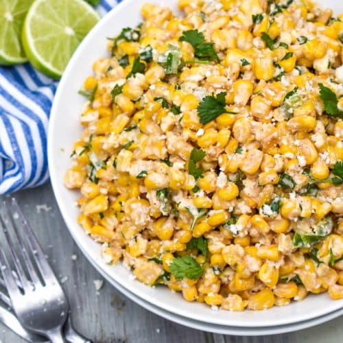 mexican street corn salad in a white bowl topped with crumbled cotija cheese and fresh cilantro leaves