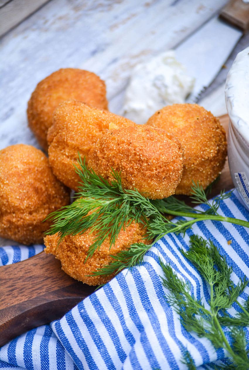 homemade hushpuppies in a pile with a fresh sprig of dill weed