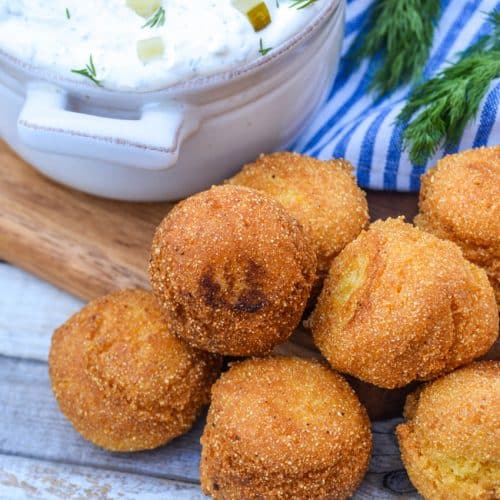 easy homemade hushpuppies in a pile in front of a gray bowl filled with dill pickle dip