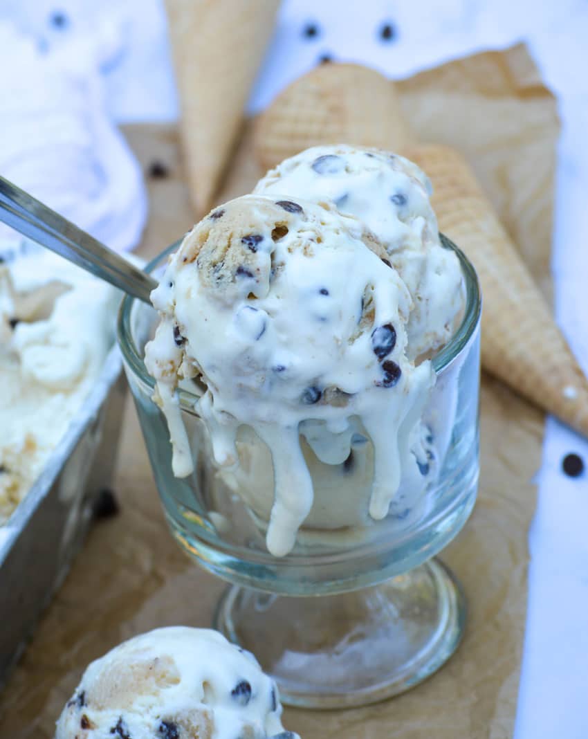 scoops of chocolate chip cookie dough ice cream melting down the sides of a glass bowl