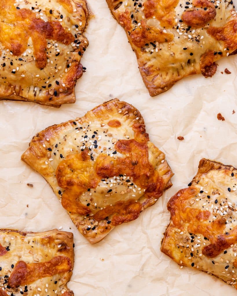 cheesy baked breakfast hand pies on a parchment lined baking sheet