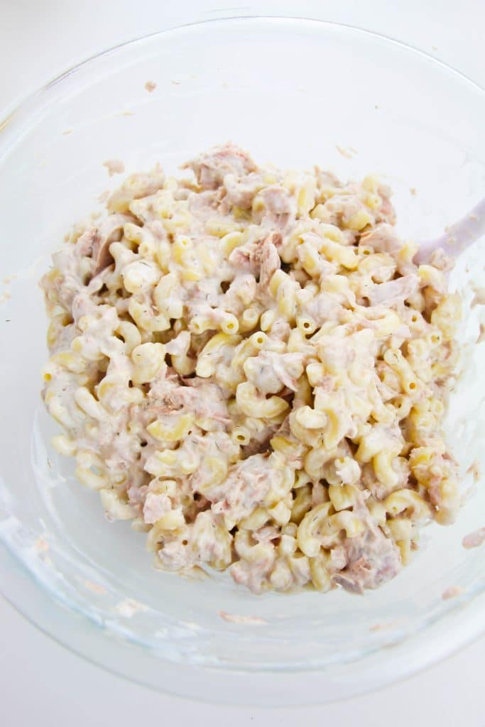 cooked elbow noodle pasta tossed in a creamy dressing in a glass mixing bowl