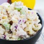 tuna macaroni salad in a black bowl with a lemon and red onion in the background