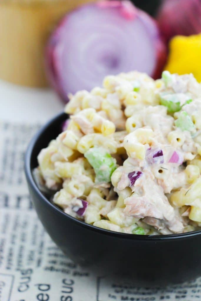 tuna macaroni salad in a black bowl with a lemon and red onion in the background