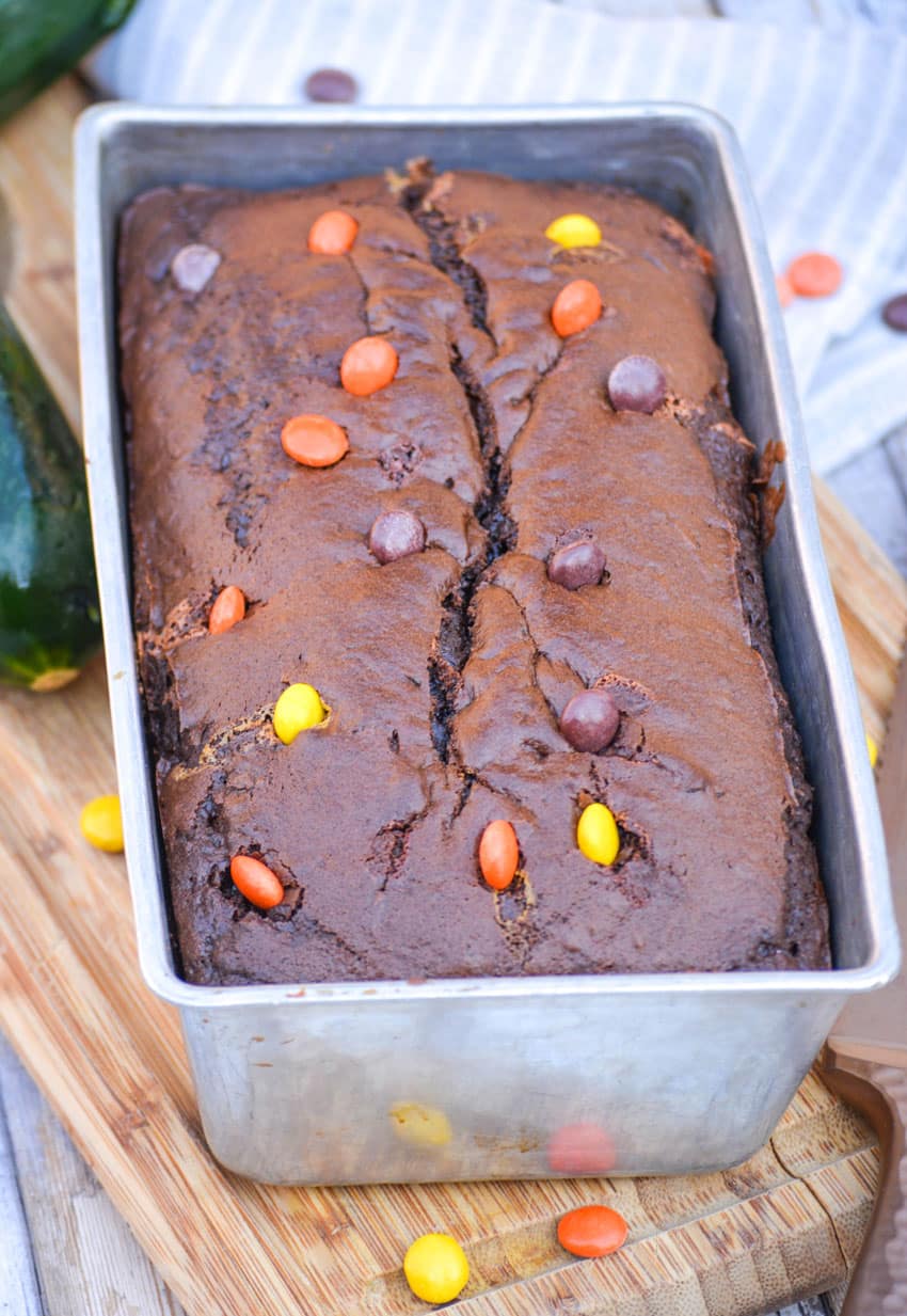 chocolate zucchini bread topped with reese's pieces in a metal loaf pan