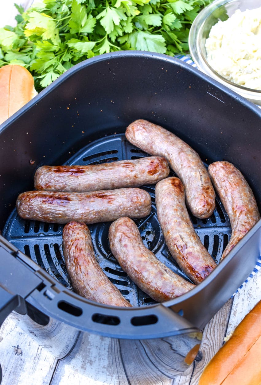 cooked beer brats in the basket of an air fryer