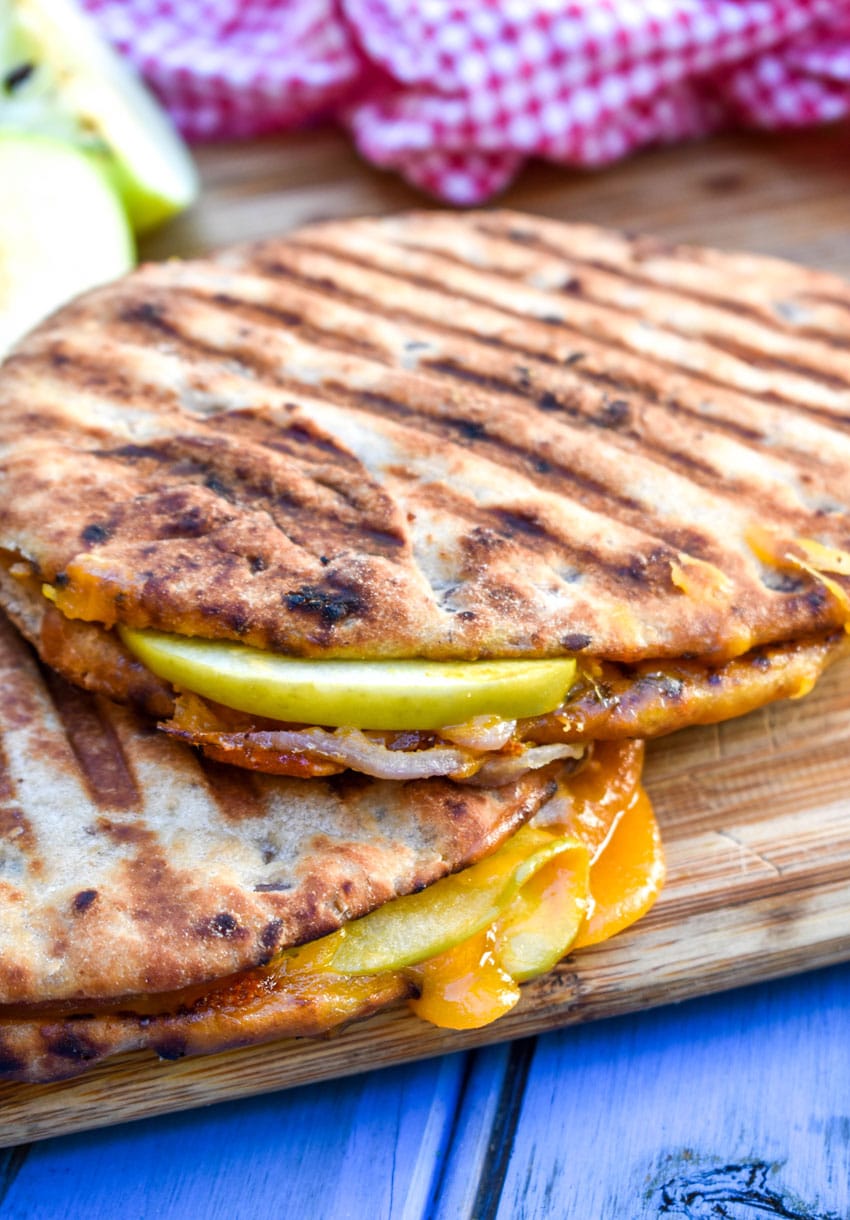 apple cheddar and onion paninis on a wooden cutting board