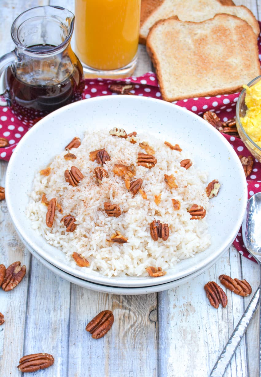 breakfast rice in a white bowl topped with pecans and crumbled bacon