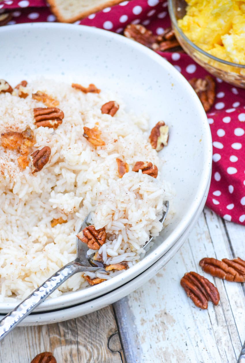 a silver spoon digging into a white bowl filled with breakfast rice