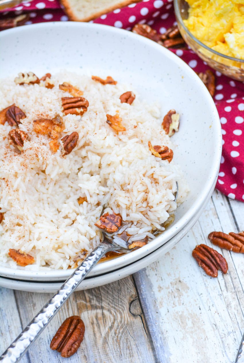 a silver spoon digging into a white bowl filled with breakfast rice