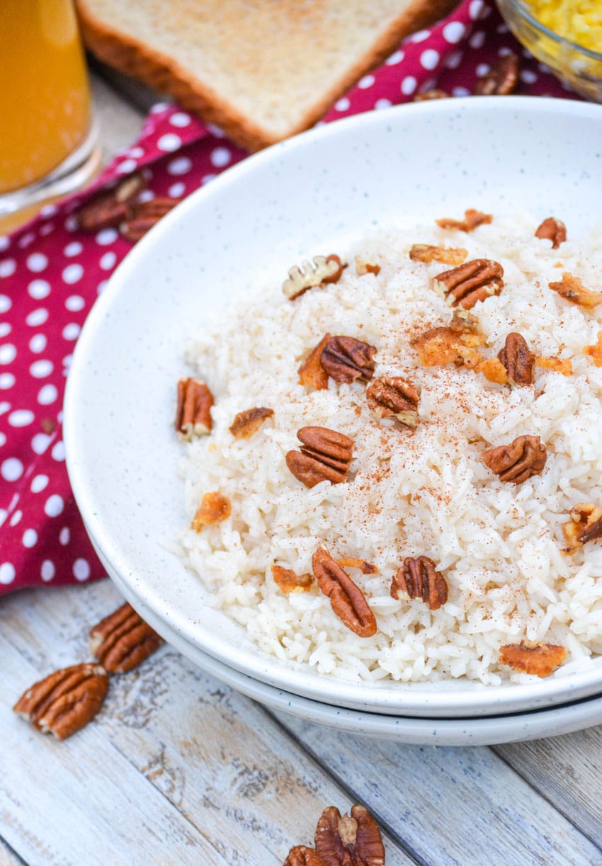 breakfast rice in a white bowl topped with pecans and crumbled bacon