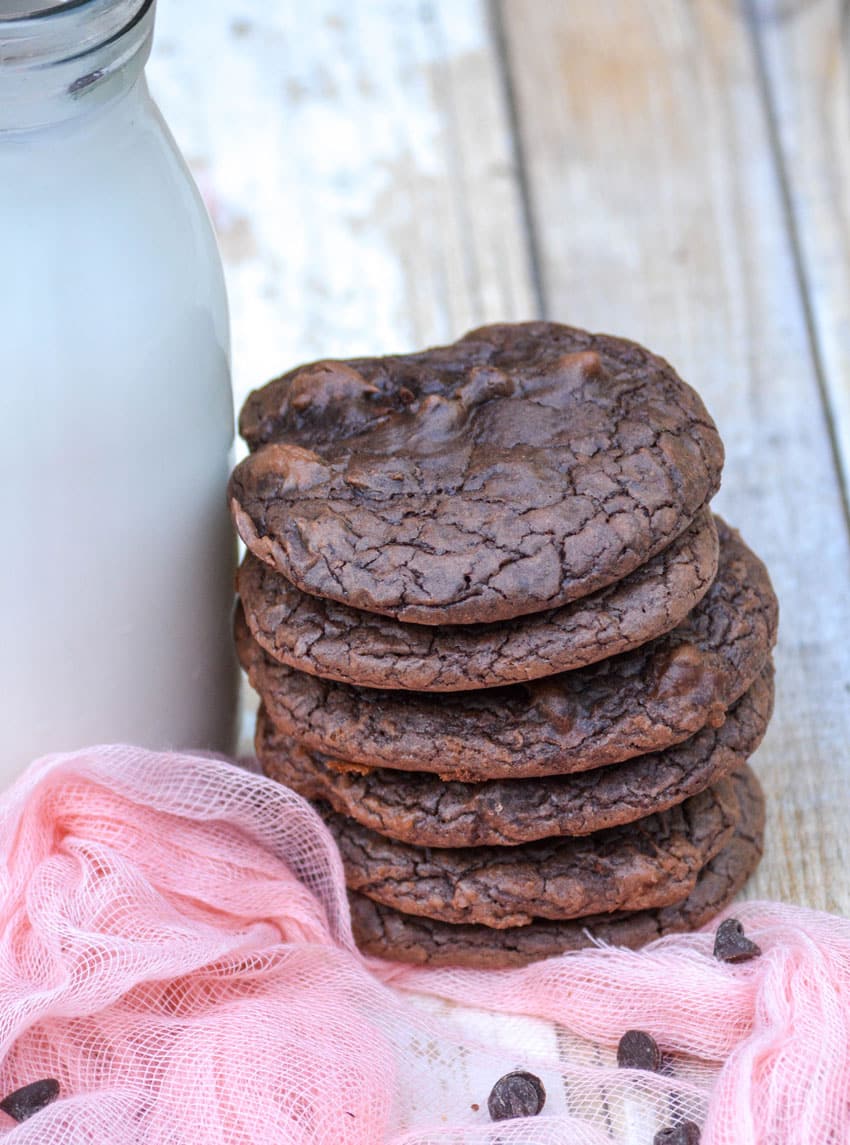 a stack of brownie cookies next to a glass of milk